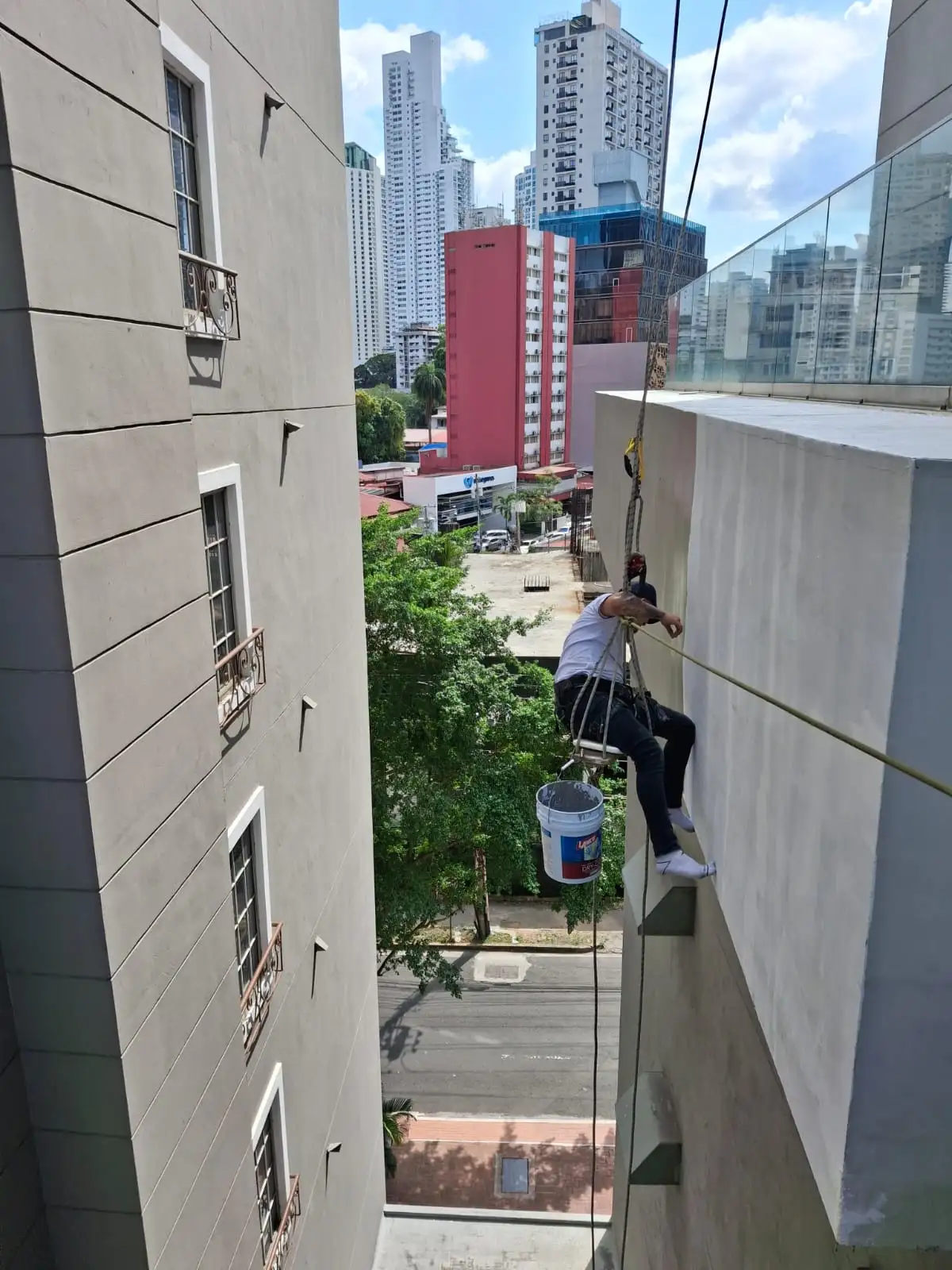 Técnico pintando fachada en sillín